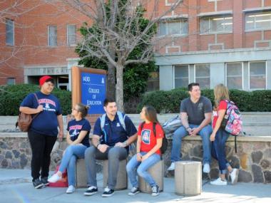 students sitting and standing in front of the college of education building